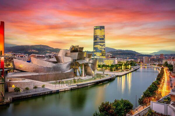 The cityscape of Bilbao at sunset. The Nervion river crosses Bilbao downtown, hosting in its margins the traditional and modern buildings of the city with the  Guggenheim Museum and Iberdrola tower.