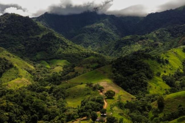 An aerial shot of a green valley between mountain peaks.